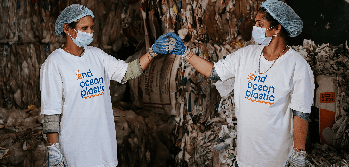 Workers in end ocean plastic shirts fist bumping